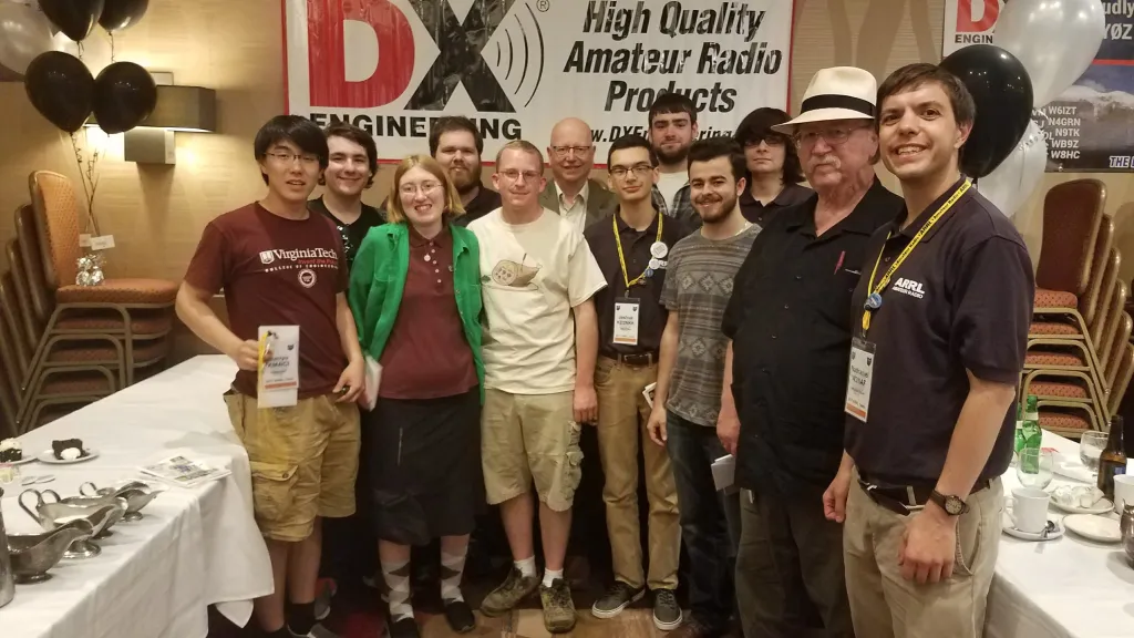 That student then donated the prize to Virginia Tech Amateur Radio Association K4KDJ. (L-R) Harry Han KM4ICI, Spencer Gunning K2AEM, Magda Moses KM4EGE, Josh Katz KD2JAO, Andy Amrhein KB3WPR, Mike Walker VA3MW, Josh Vega KD2NKK, Nick Zito KD2MCS, Chris Harrsch KD2GYD, Brendan Keogan KD2LXD, Mike Clarson WV2ZOW, and Nathaniel Frissell W2NAF